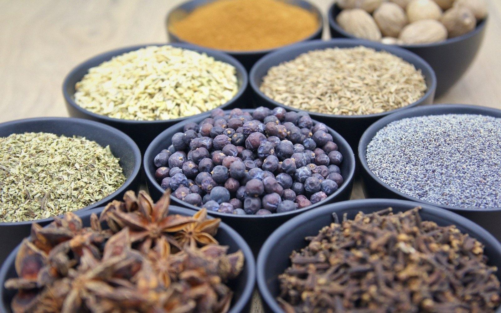 Small black bowls hold star anise, cloves, poppy seeds, juniper berries and ground spices