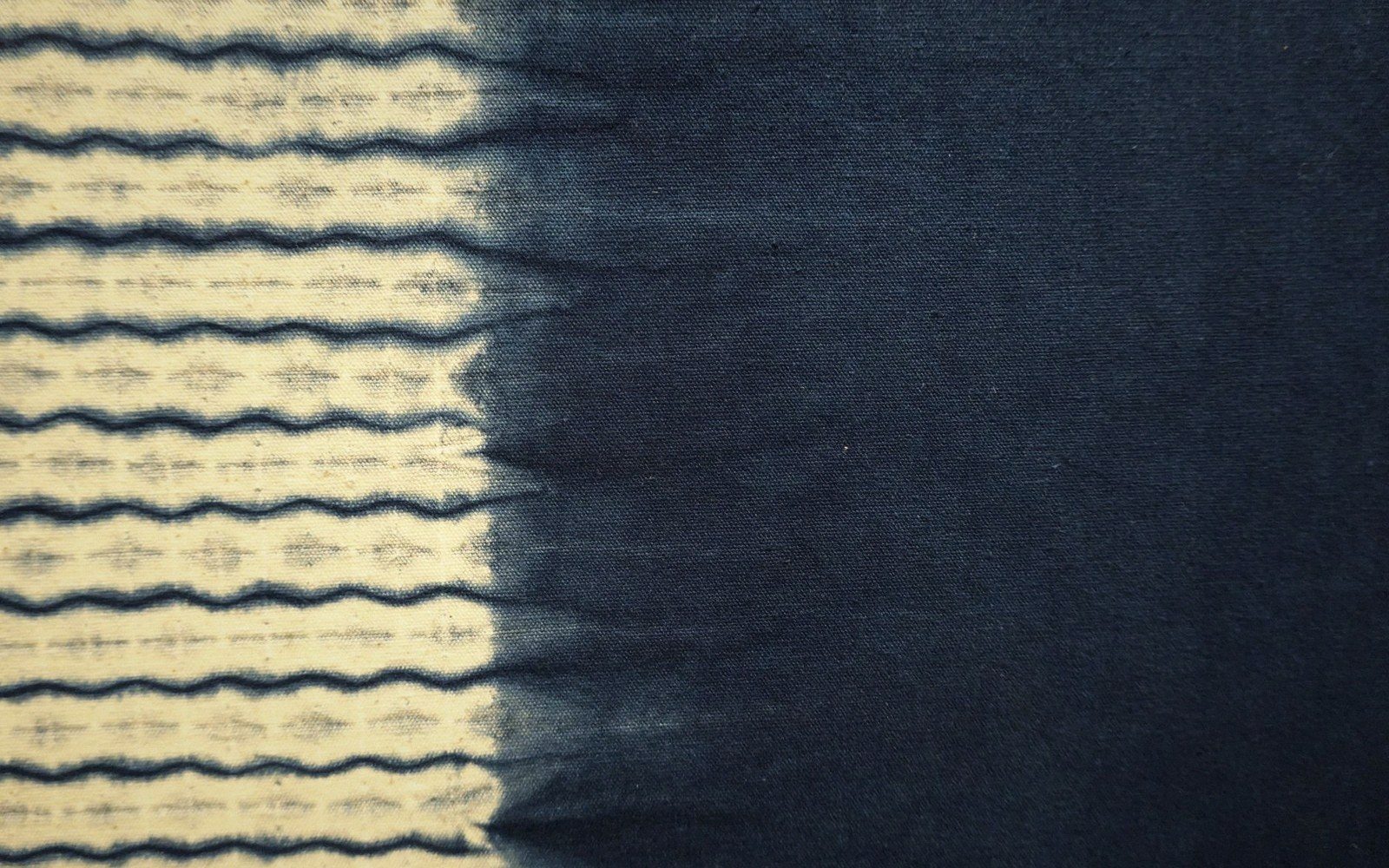 Wavy indigo shibori pattern on cotton fades into solid dark blue dyed fabric