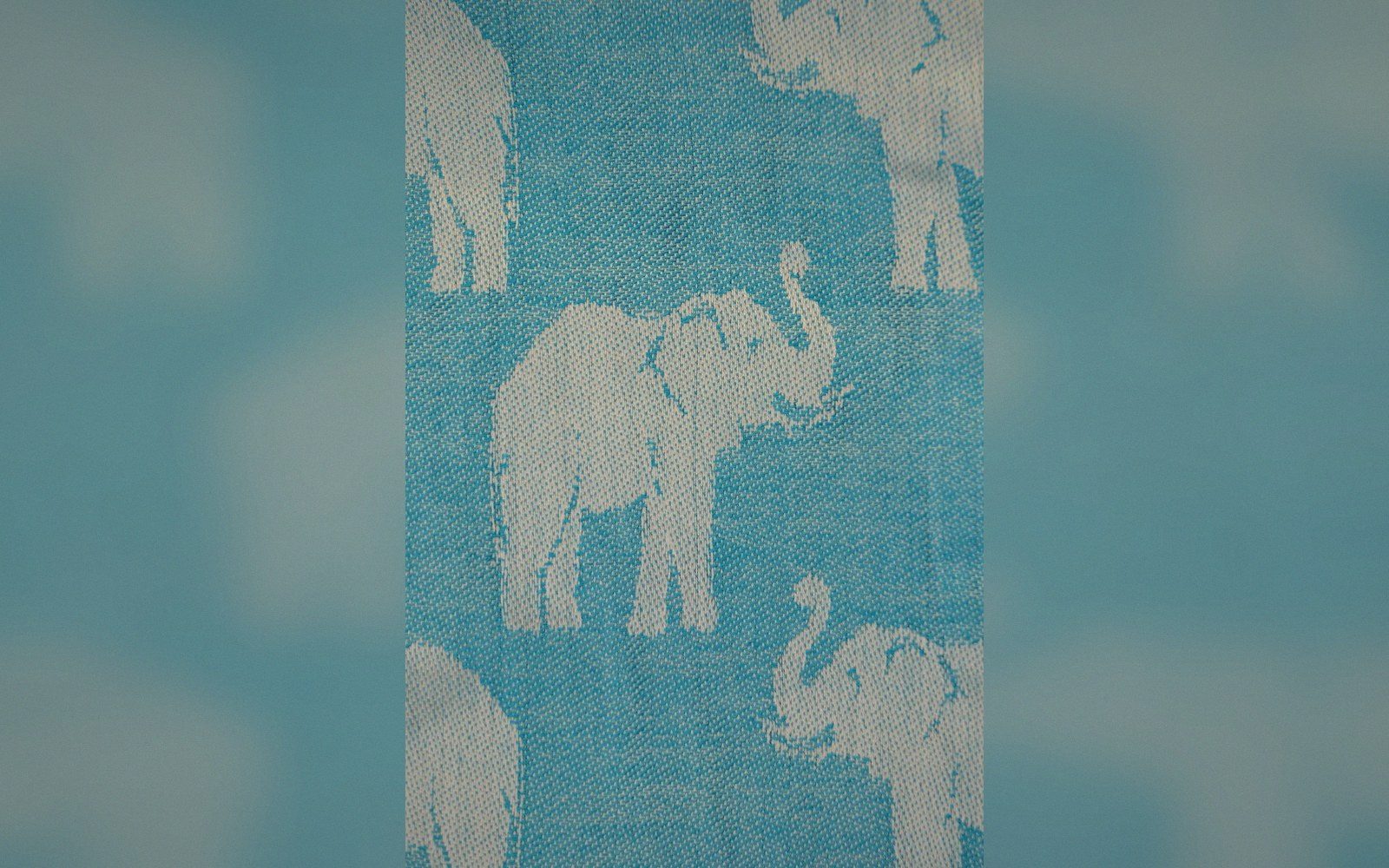 Woven fabric featuring a repeating pattern of white elephants on a turquoise background